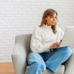 pretty-woman-with-blond-wavy-hairs-sitting-sofa-home-working-laptop-computer_273443-4616